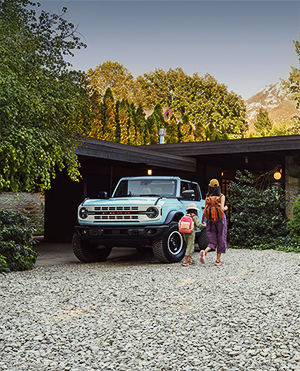 Family walking toward house with parked SUV in driveway